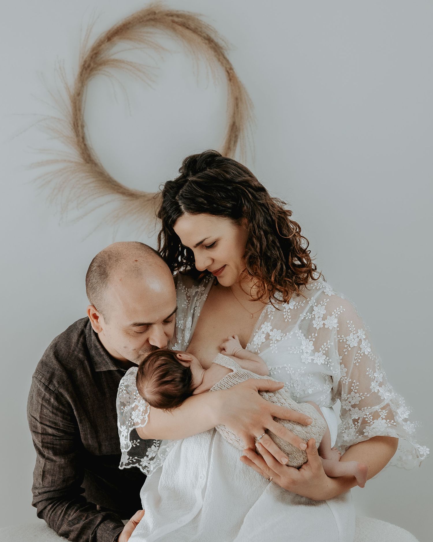 Mamma e papà abbracciano il loro neonato nello studio fotografico