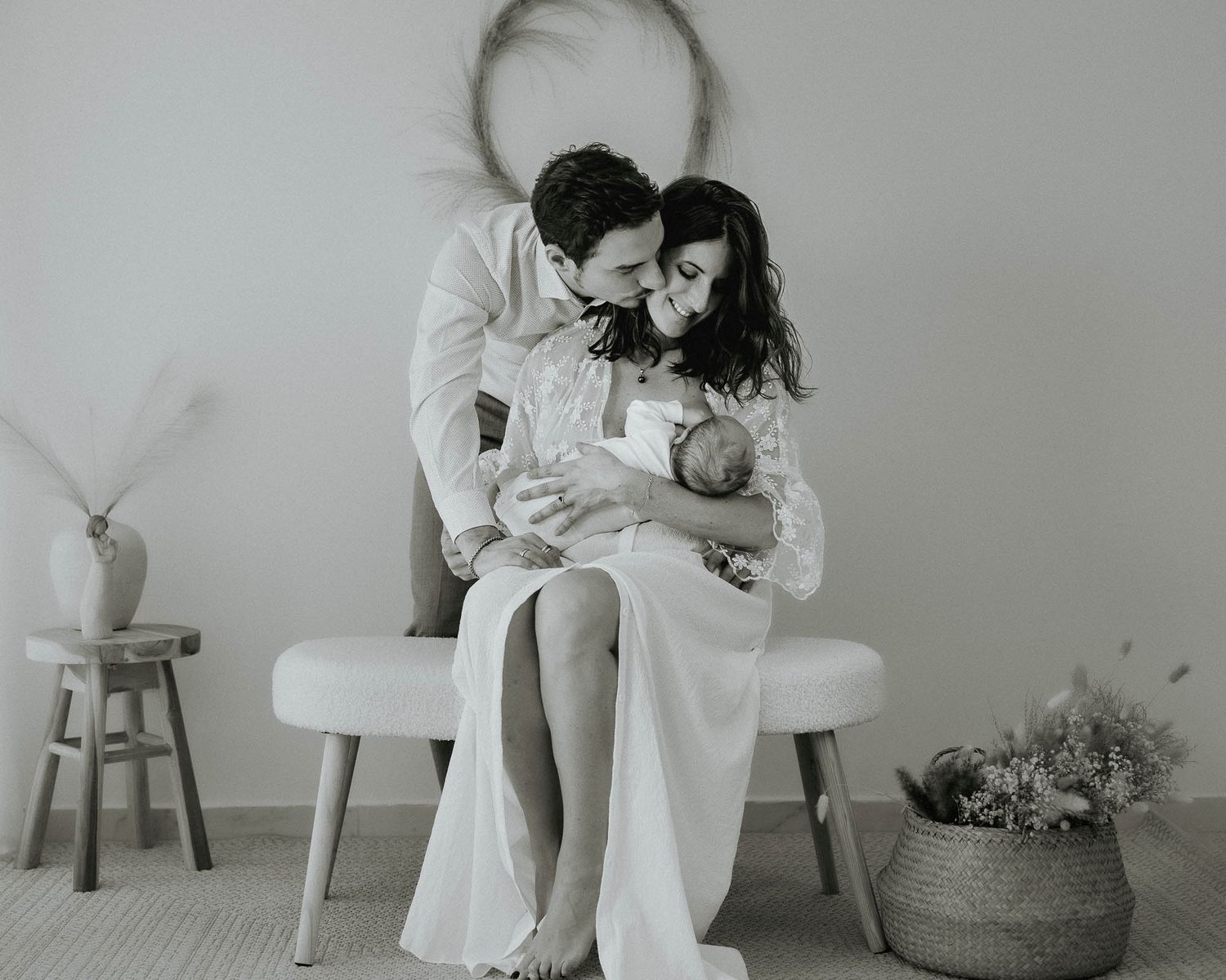 Black and white newborn family portrait of parents sitting together lovingly holding their newborn baby.
