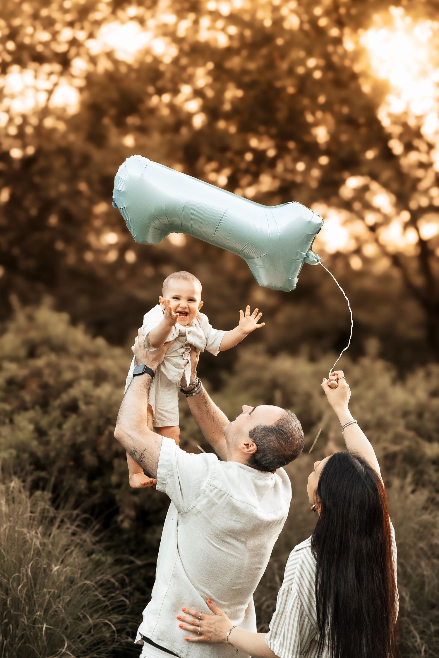 Famiglia durante un servizio fotografico per il primo compleanno con palloncino a forma di numero uno