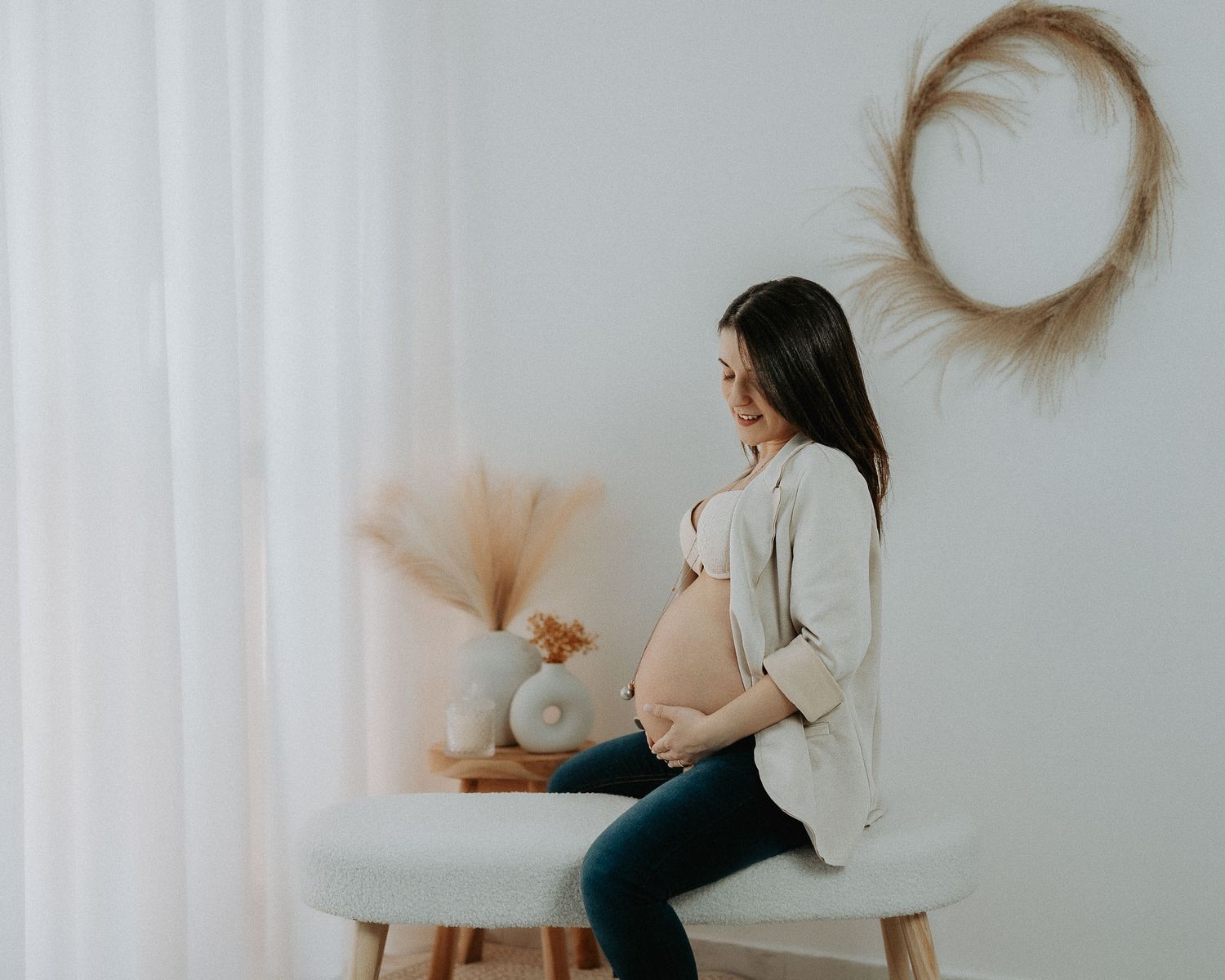servizio fotografico gravidanza naturale in studio a Milano con futura mamma seduta e mani sul pancione