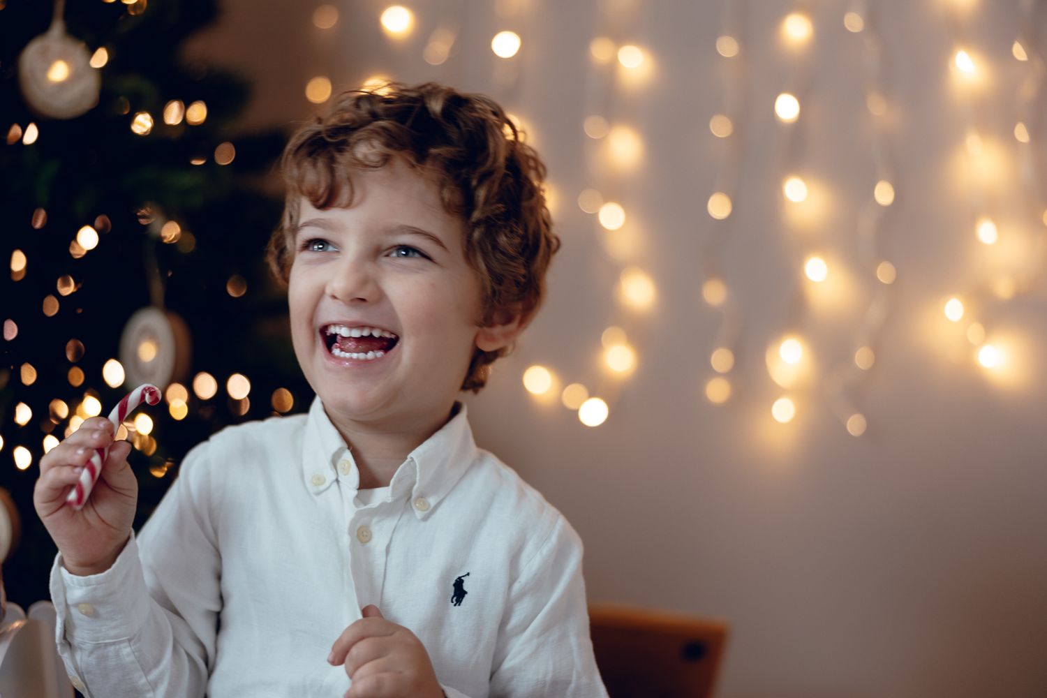 Joyful expressions captured during family Christmas photoshoot with twinkling lights.