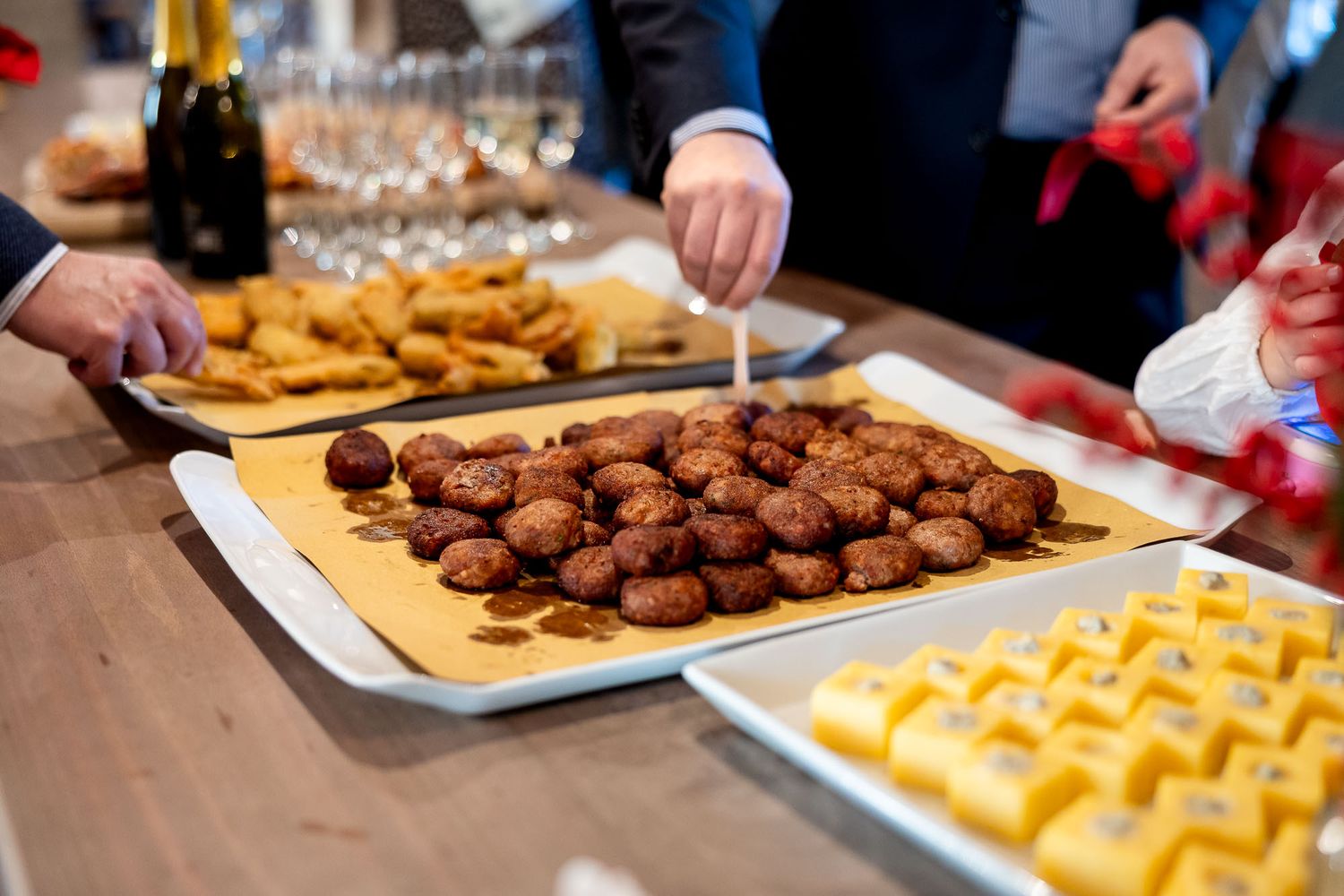 Buffet table with meatballs, fried appetizers, and yellow cheese cubes on trays at a catered party event.