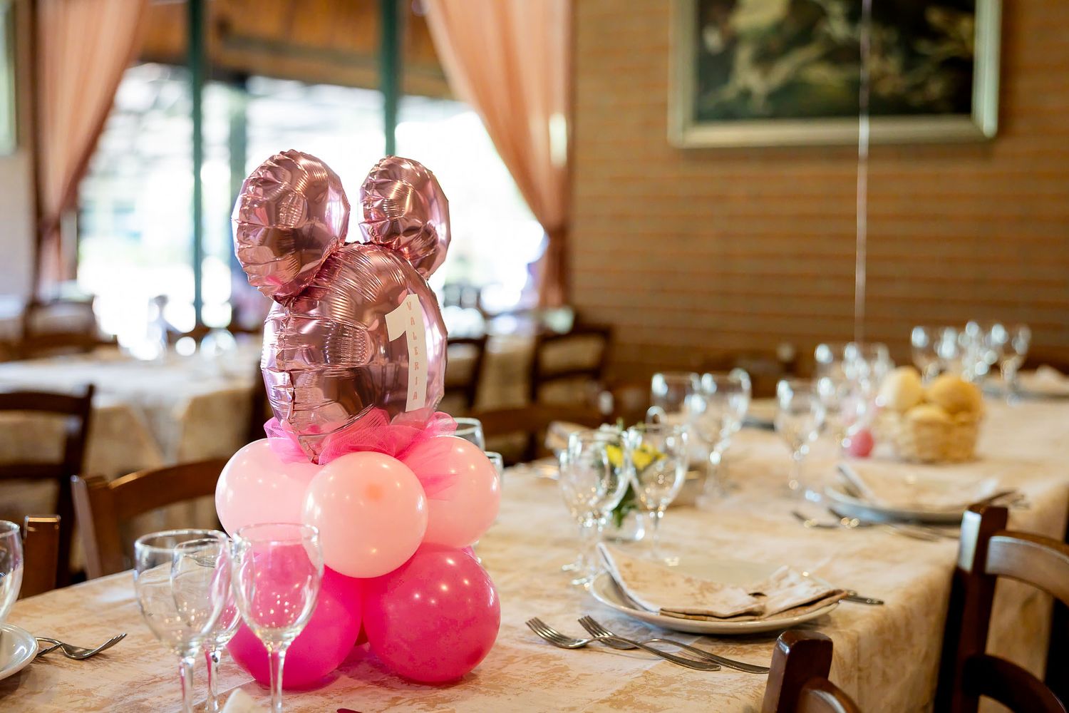 Pink balloon centerpiece with Minnie Mouse balloons on a decorated banquet table set for a celebration event.