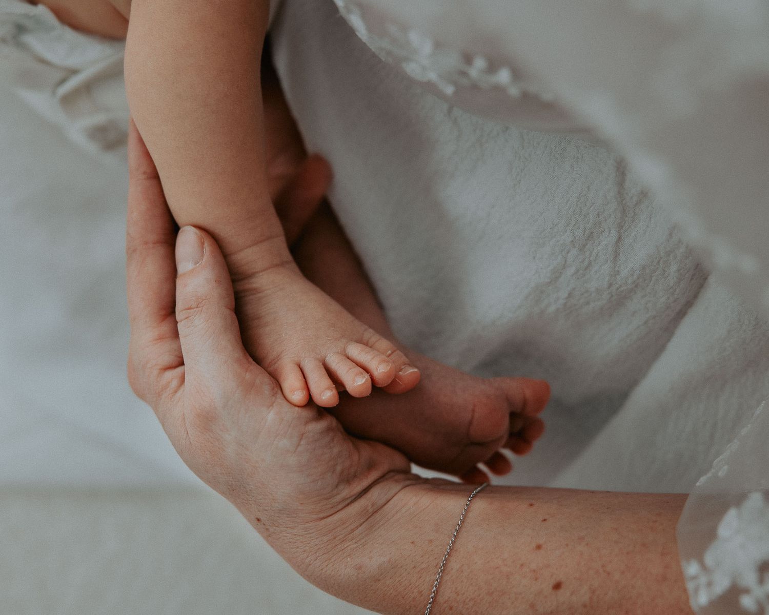 Piedino del neonato appoggiato sulla mano della mamma.