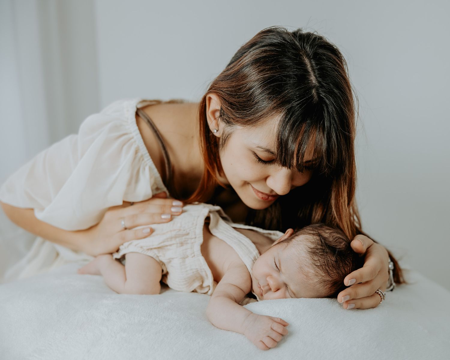 Mamma che bacia il suo neonato disteso sul lettino.