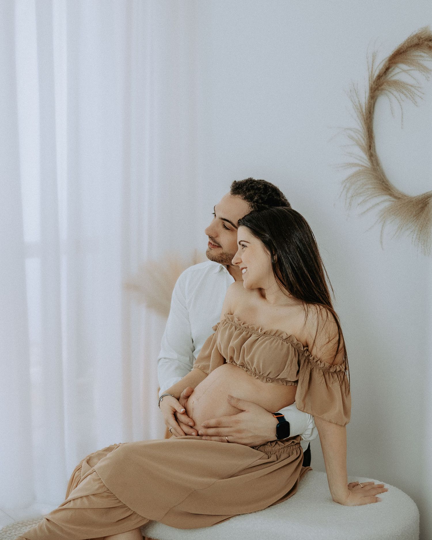 Fotografia maternity elegante in studio fotografico a Milano con abito beige e sfondo minimal
