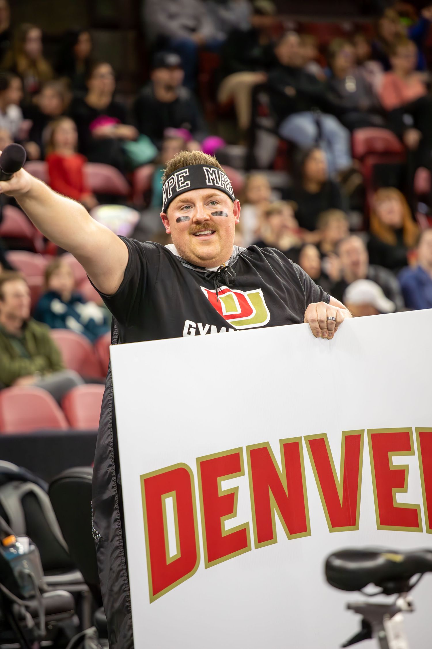 Sports fans hold up individual letters spelling out 'DENVER' at a stadium event.
