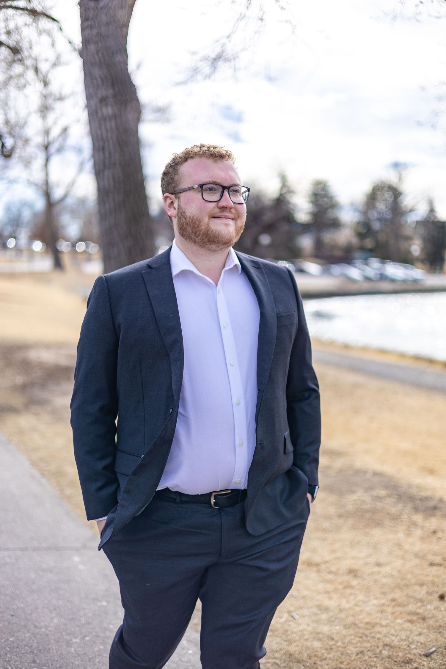 Professional portrait session outdoors in winter showing person in navy suit and white shirt against snowy landscape.