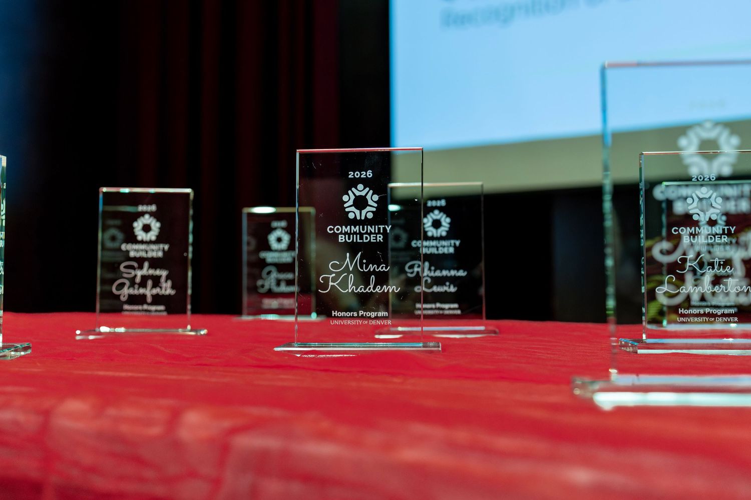 Crystal recognition awards displayed on a red tablecloth at a community builder awards ceremony.