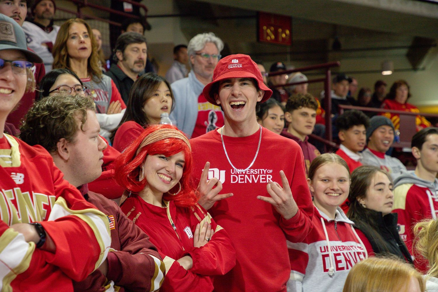 Crowd of excited fans in red jerseys and apparel cheering enthusiastically at a sporting event.