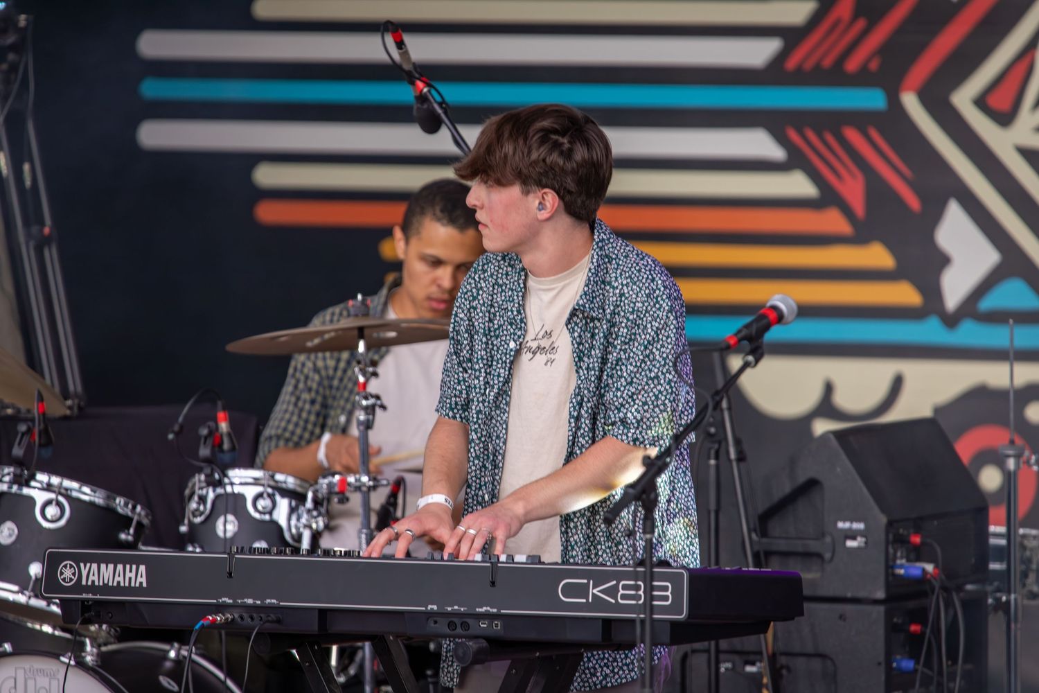 Musicians performing on electronic keyboards at an outdoor concert event.