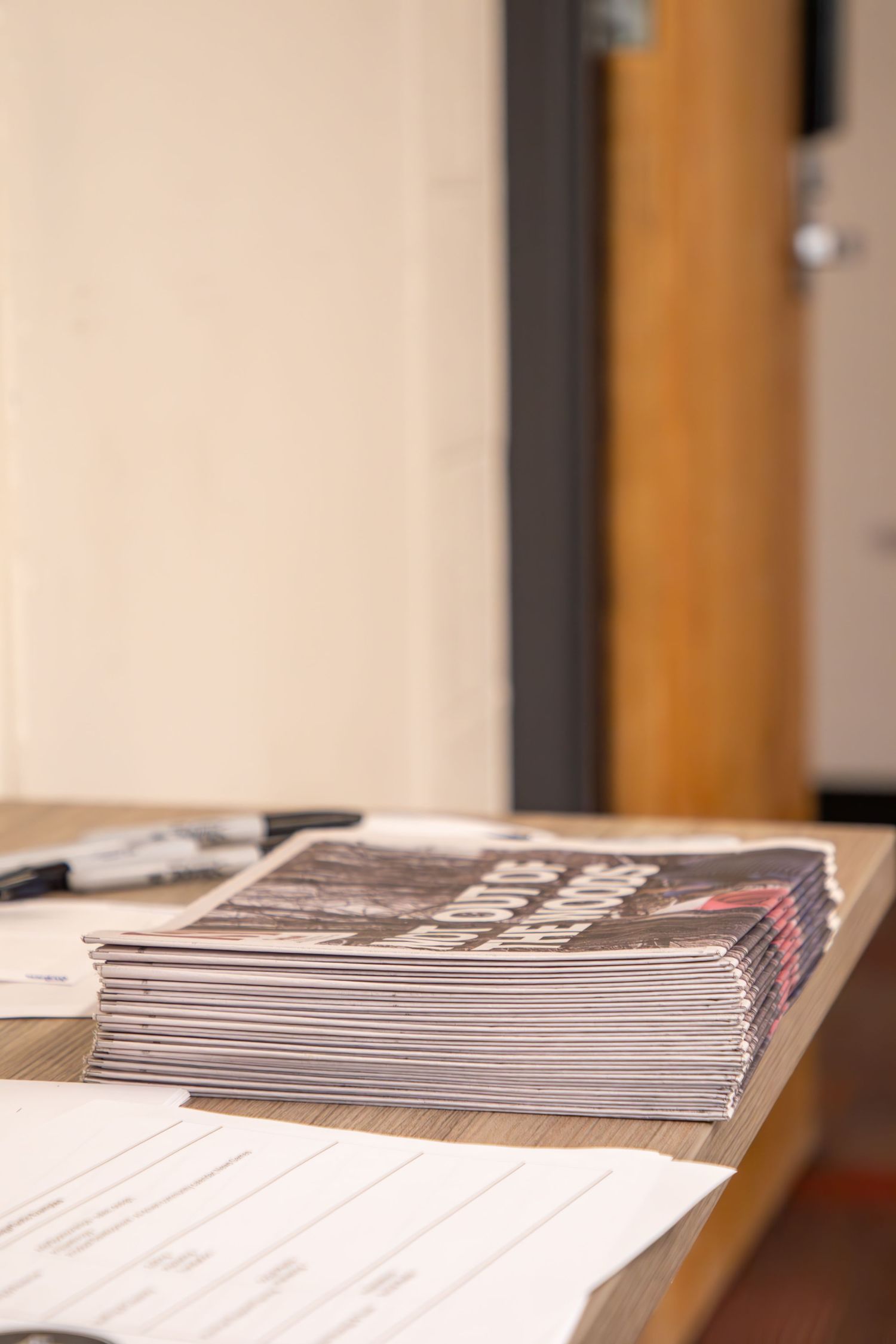 Stack of printed campaign materials and documents on a desk near a wooden door.