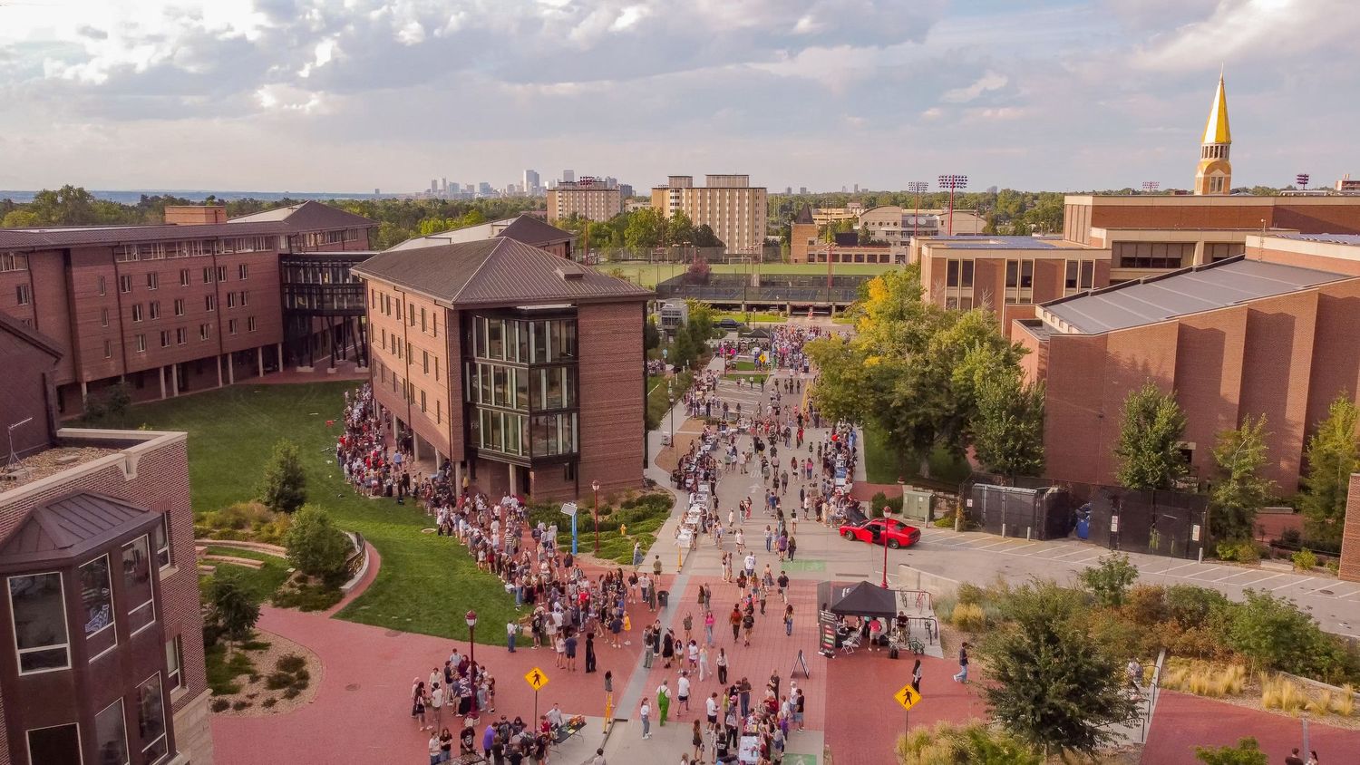 Aerial panorama of a university campus showing buildings and walkways filled with people.