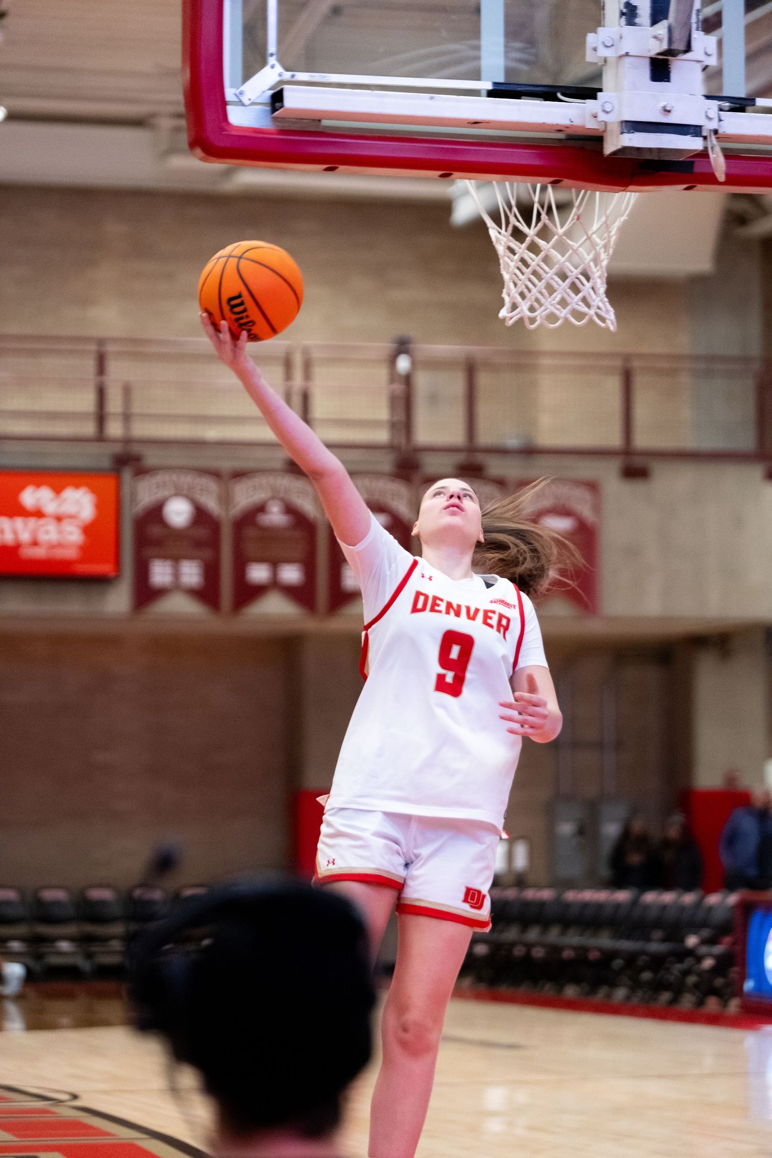 Denver Pioneers women's basketball player #9 attempts a layup during a home game at the indoor arena.