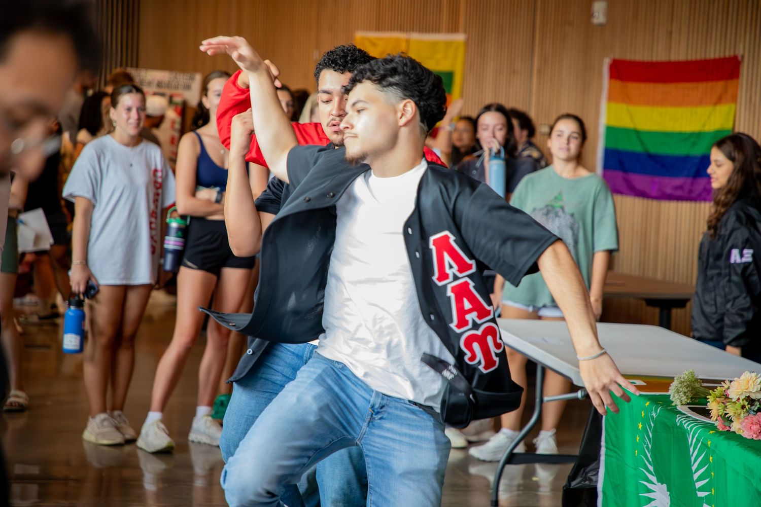 Students gather at a social event with pride flags and decorations visible in the background.