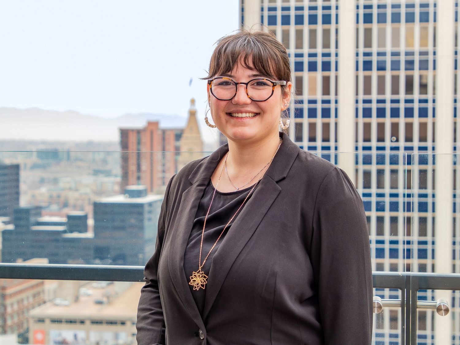 Professional headshots of team members with modern office building exterior in background.