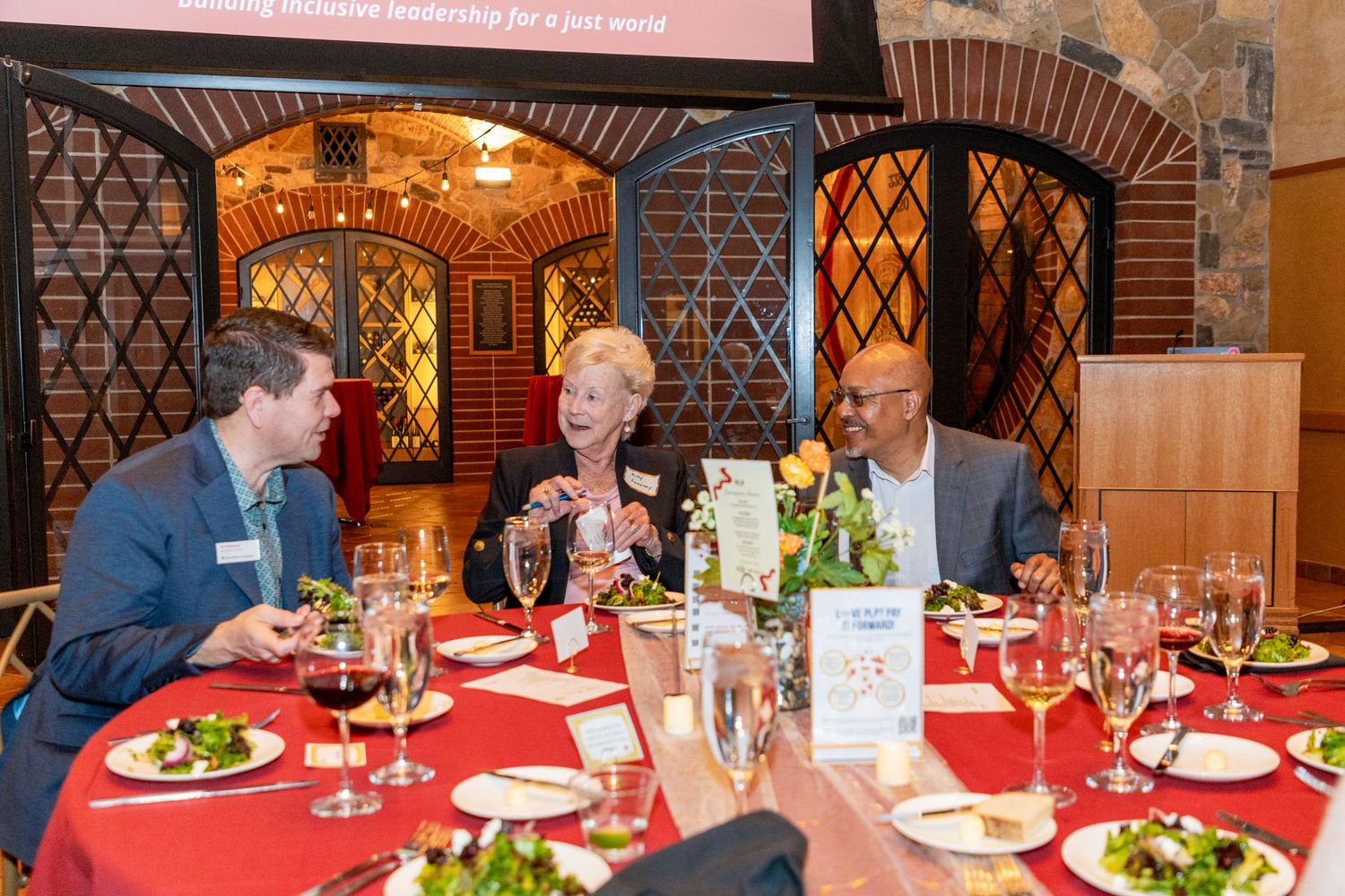 Diners enjoying a festive meal at an elegant restaurant with red tablecloths and decorative latticed walls.