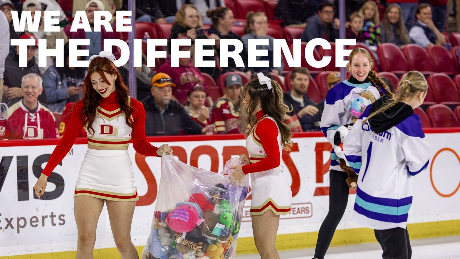 Cheerleaders and hockey player exchange toys at a rink fundraiser event with 'We Are The Difference' text overlay.