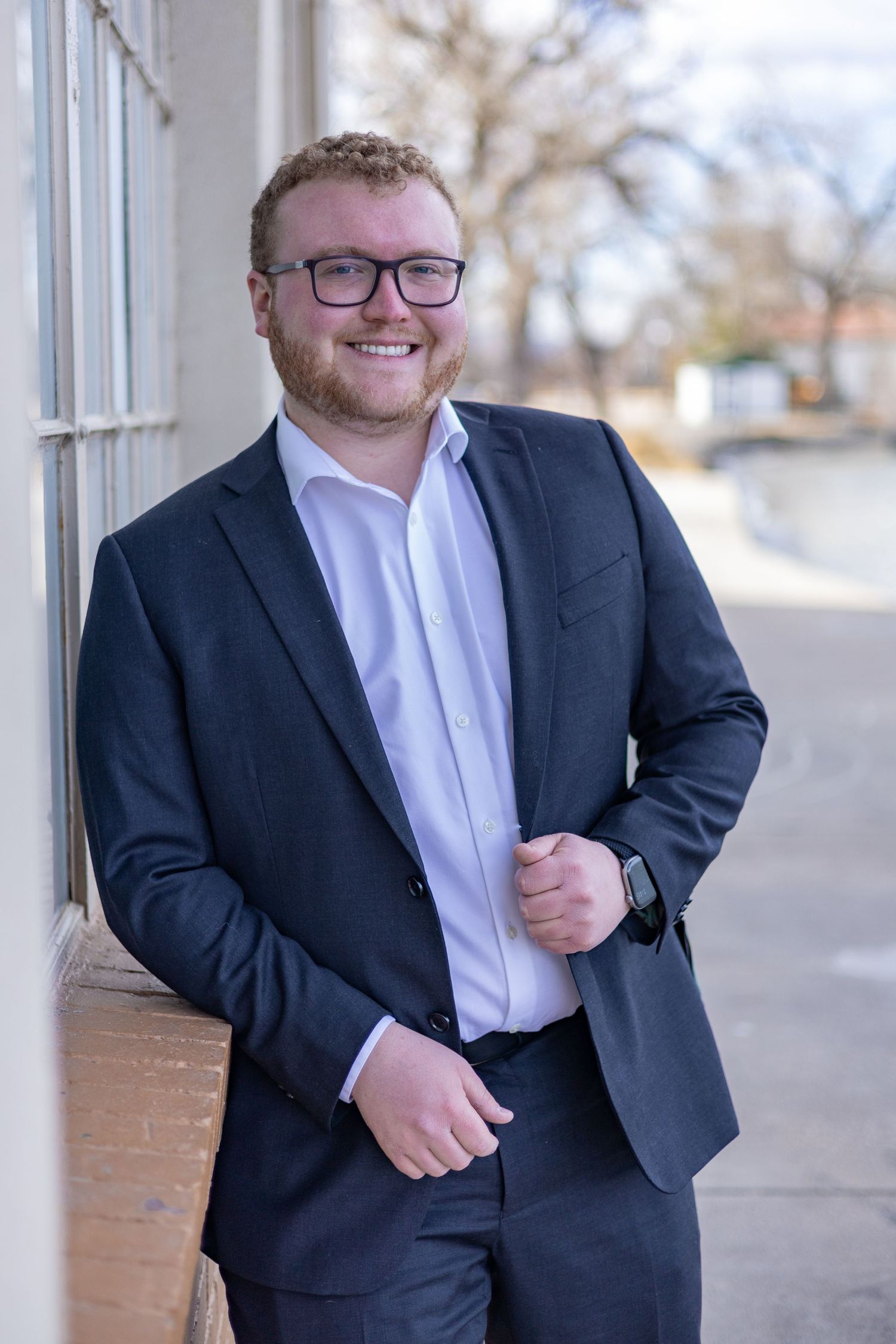Professional business portrait series showing different poses in a navy suit and white shirt against a light colored wall.