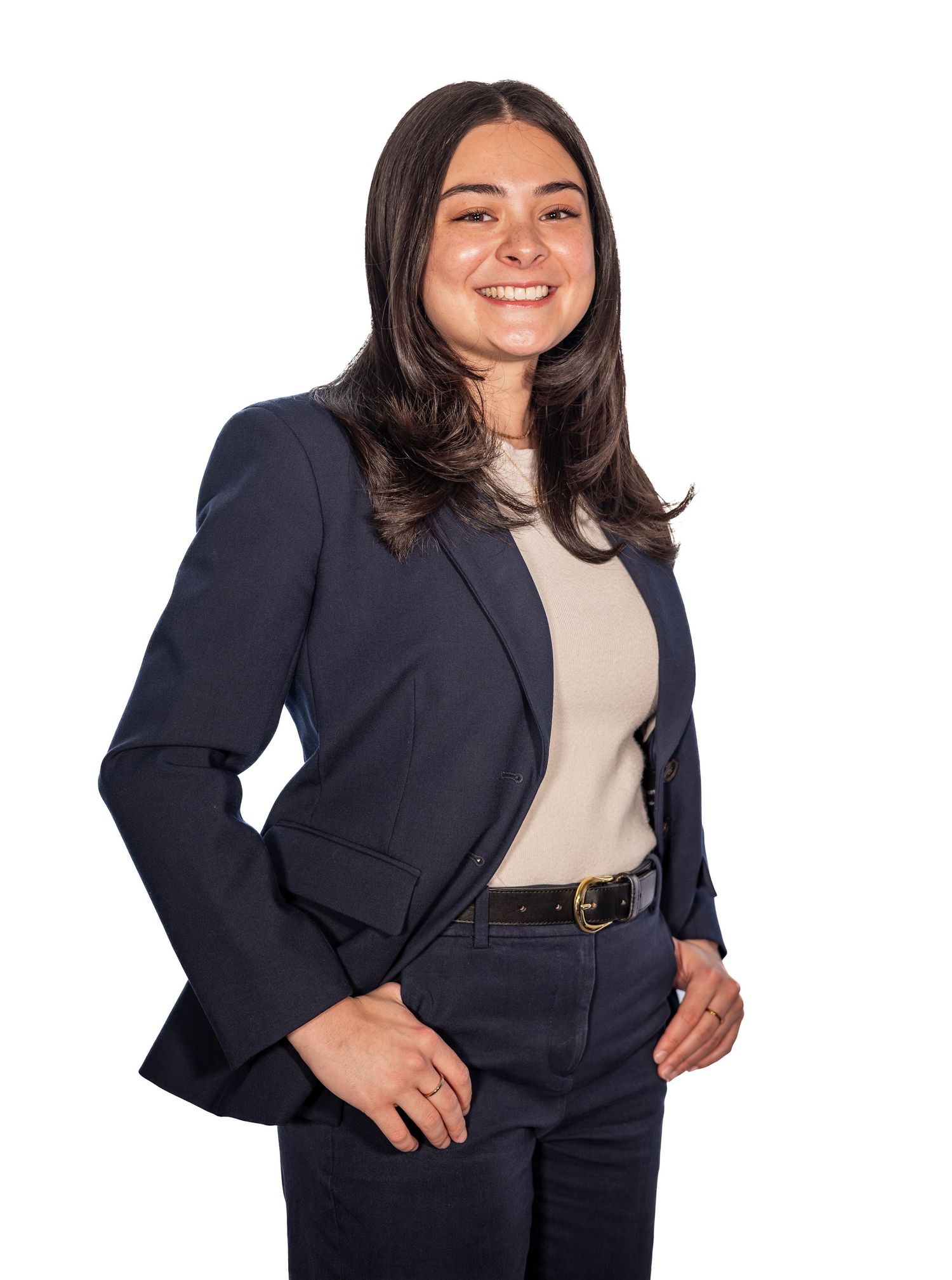 Young professional woman in navy blazer and beige top smiling confidently against white background.