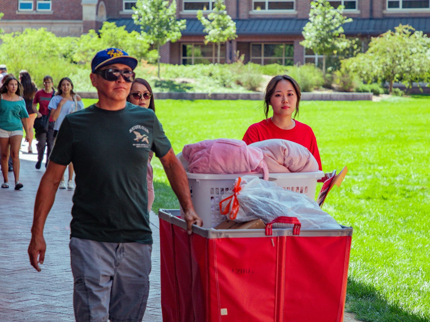 Volunteers serve food and refreshments at an outdoor community event on a sunny summer day.