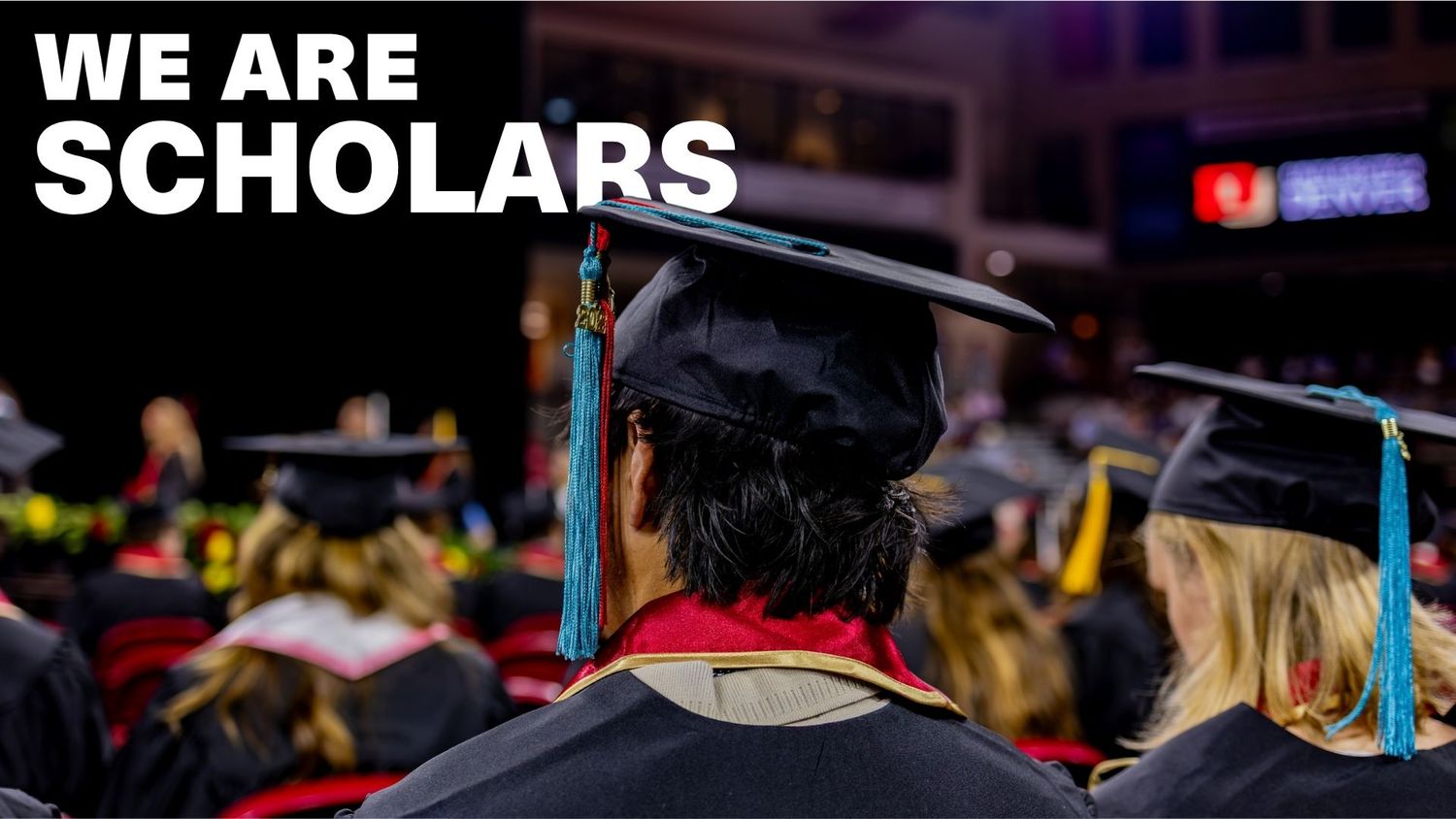 Graduates in black caps and gowns at a commencement ceremony with text reading We Are Scholars.