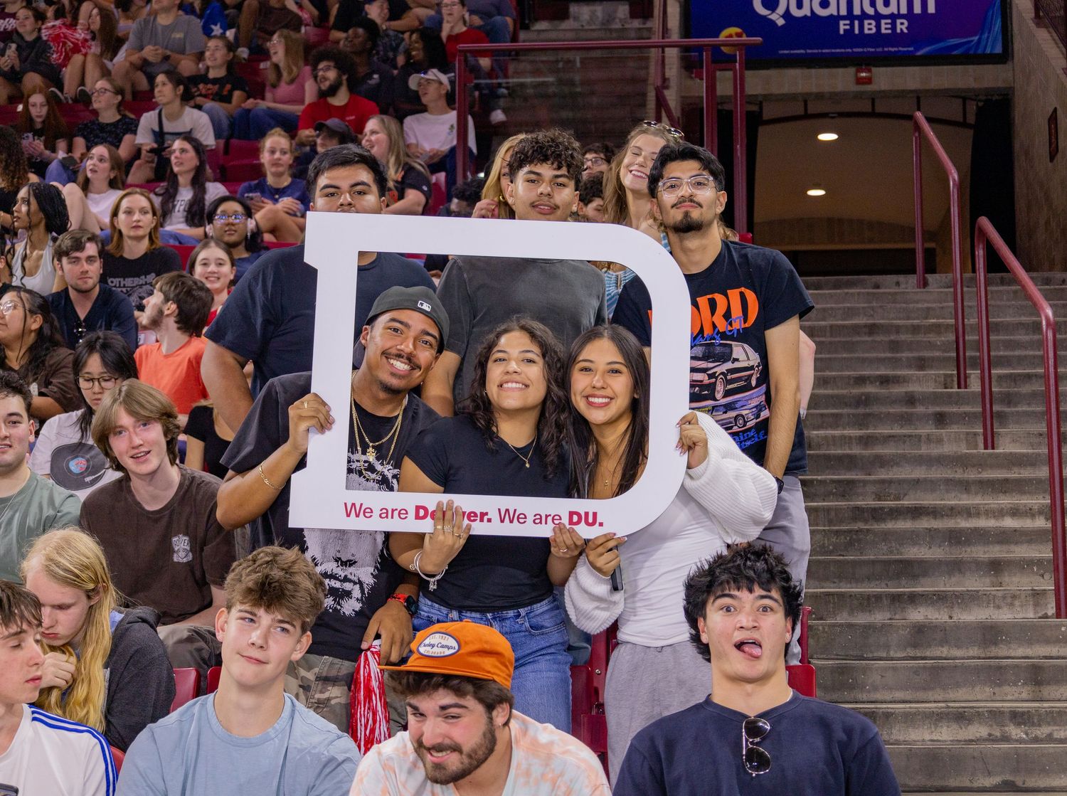 University of Denver students hold photo frame sign reading We are Denver We are DU at campus event.