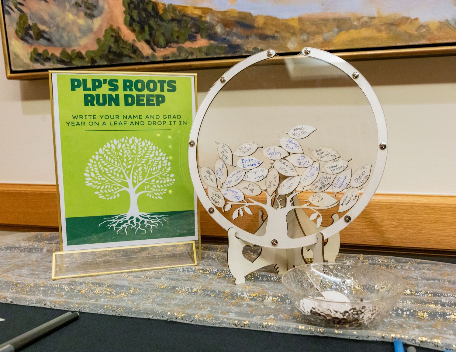 A book titled 'Plant Roots Run Deep' displayed next to a decorative white tree sculpture on a windowsill.
