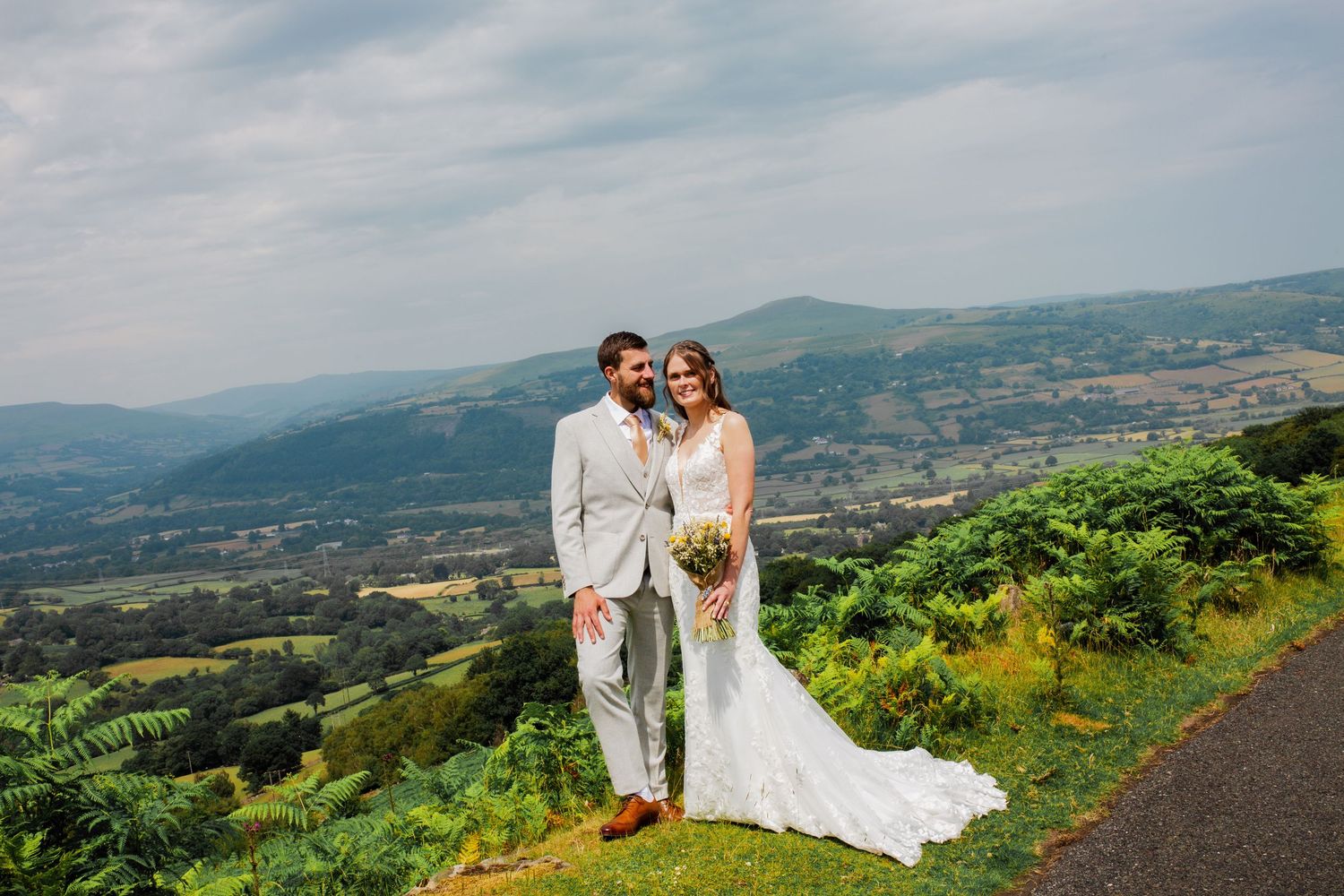 Newlyweds pose against a stunning mountainous landscape on their wedding day.