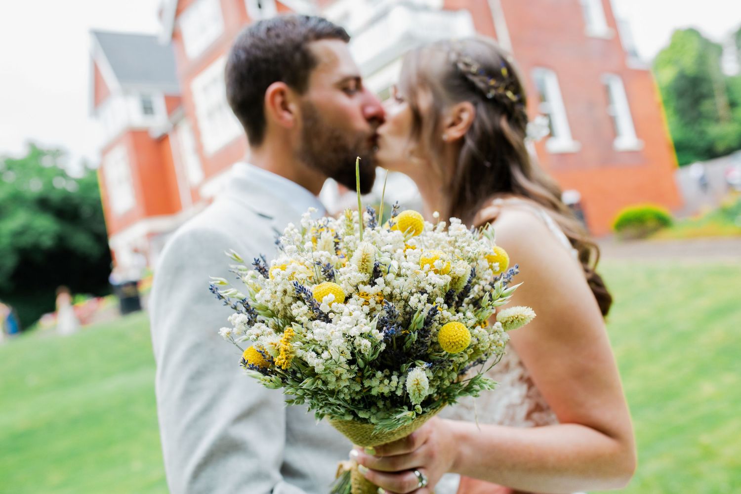 Couple sharing an intimate moment with a bouquet of yellow and white wildflowers.