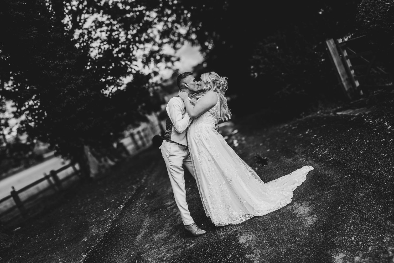 Black and white wedding photos captured in dramatic lighting among trees.