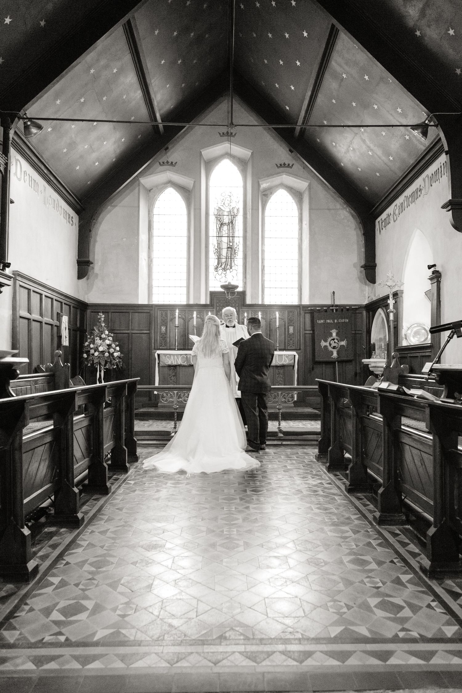 A classic church wedding ceremony photo showing a couple at the altar with stained glass windows.