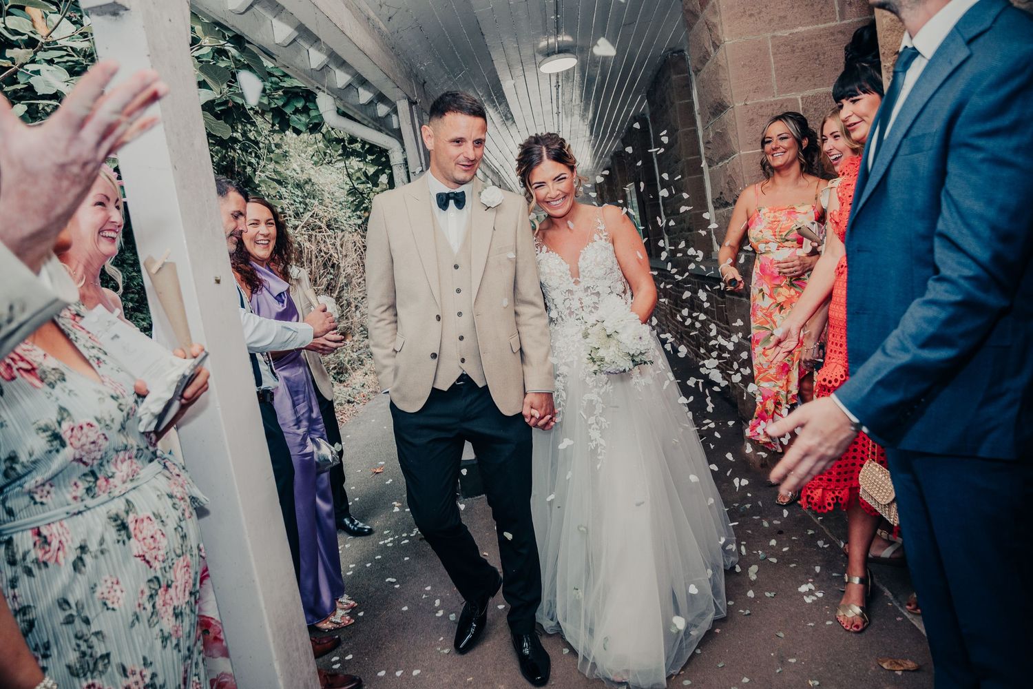 Wedding celebration at an elegant indoor venue with confetti falling from above during a romantic moment.