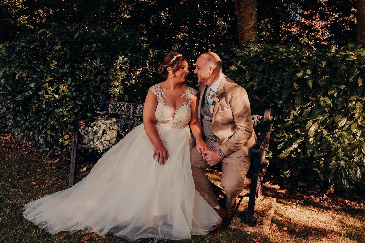 Romantic outdoor wedding photography session with natural sunlight filtering through trees.