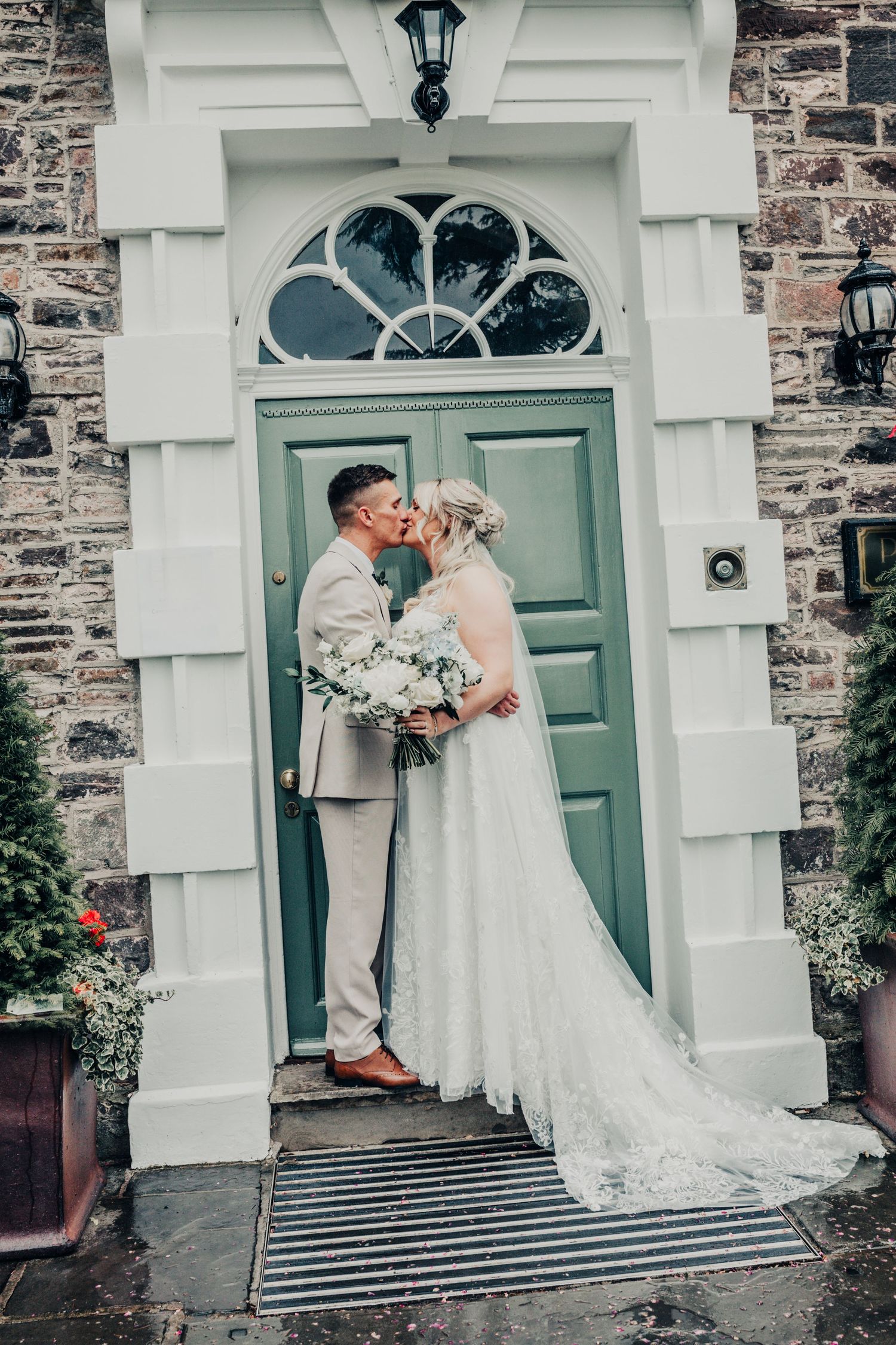 Elegant wedding couple sharing moment in front of turquoise door with stone archway.