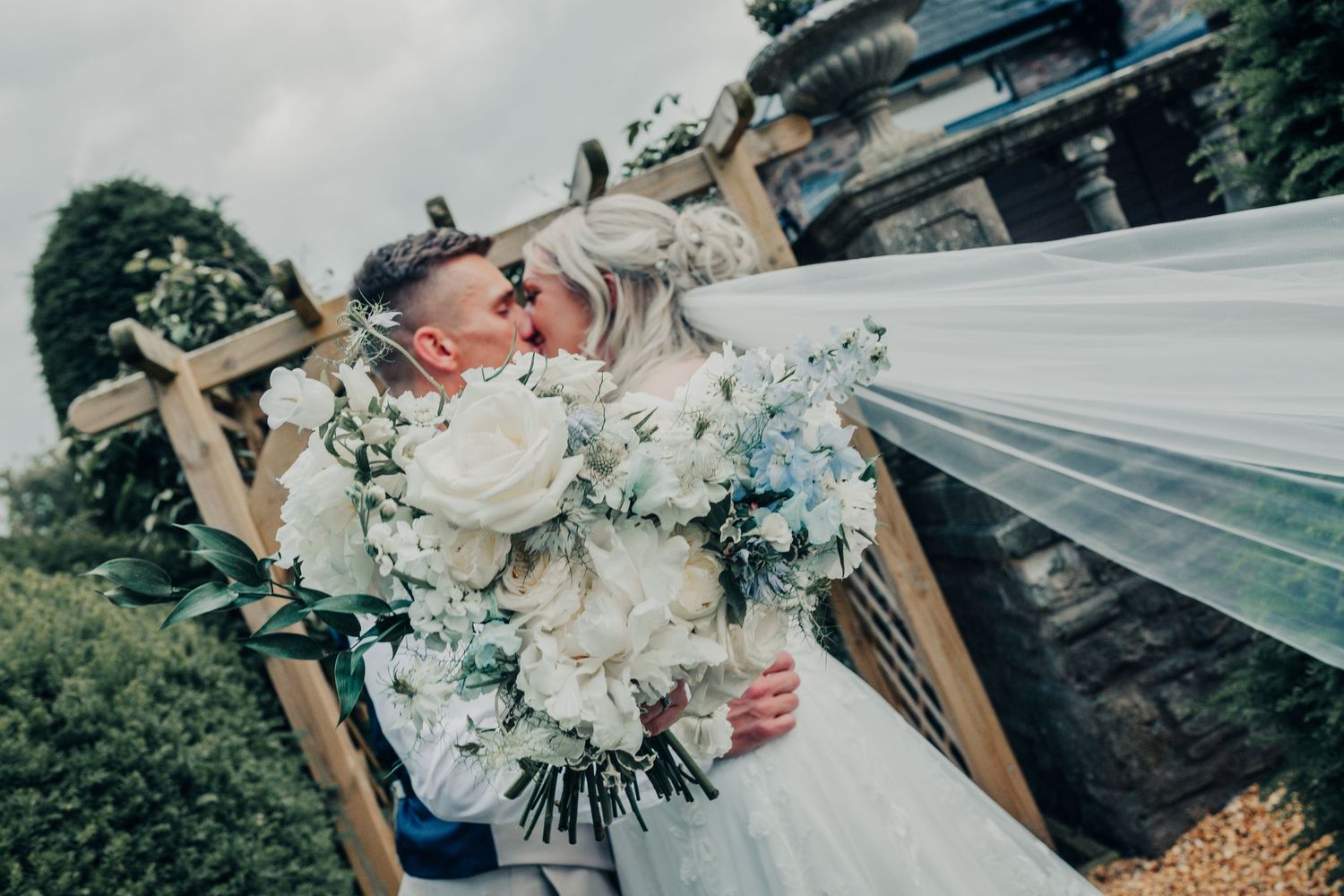 A white wedding dress and veil flow in the breeze during an outdoor photoshoot.