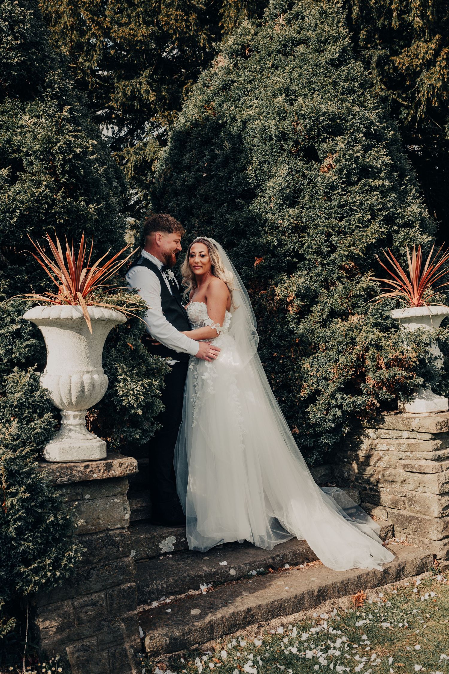 Romantic wedding portrait of couple between decorative garden urns.
