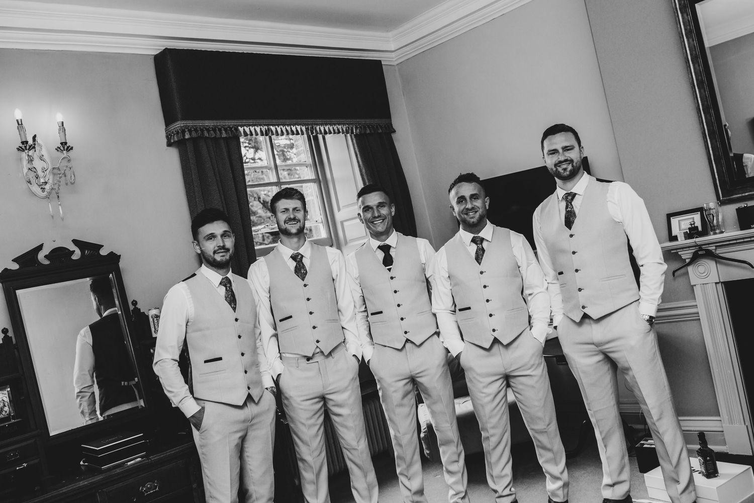 Wedding party in matching light grey waistcoats and ties posing together.