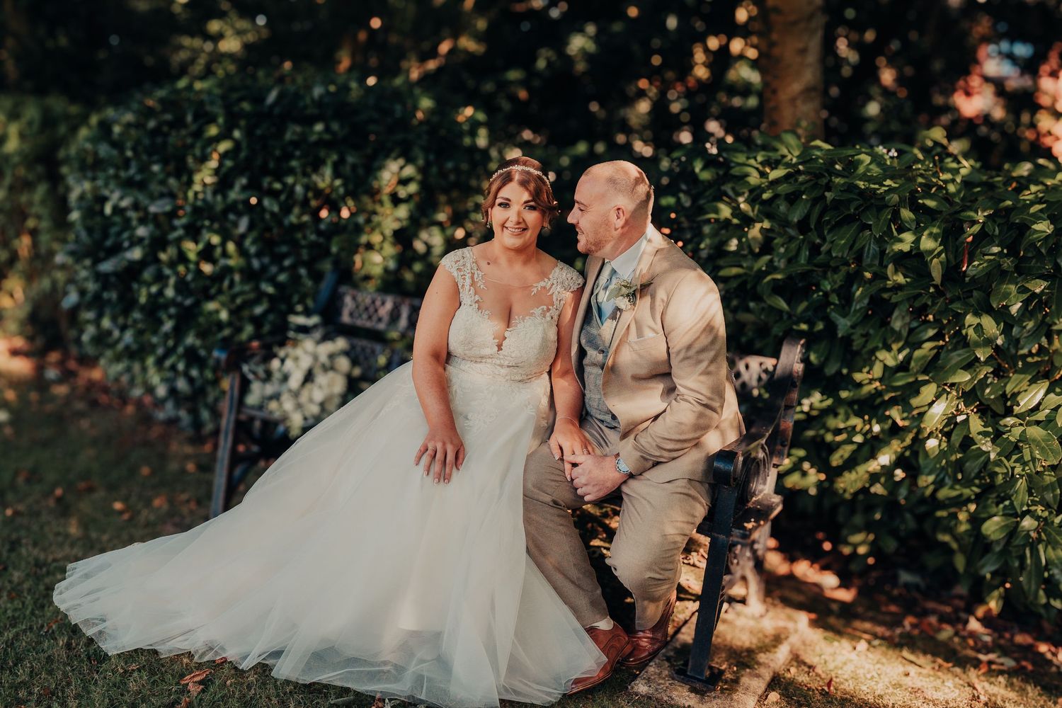 Sunlit wedding portraits captured outdoors with lush greenery in the background.