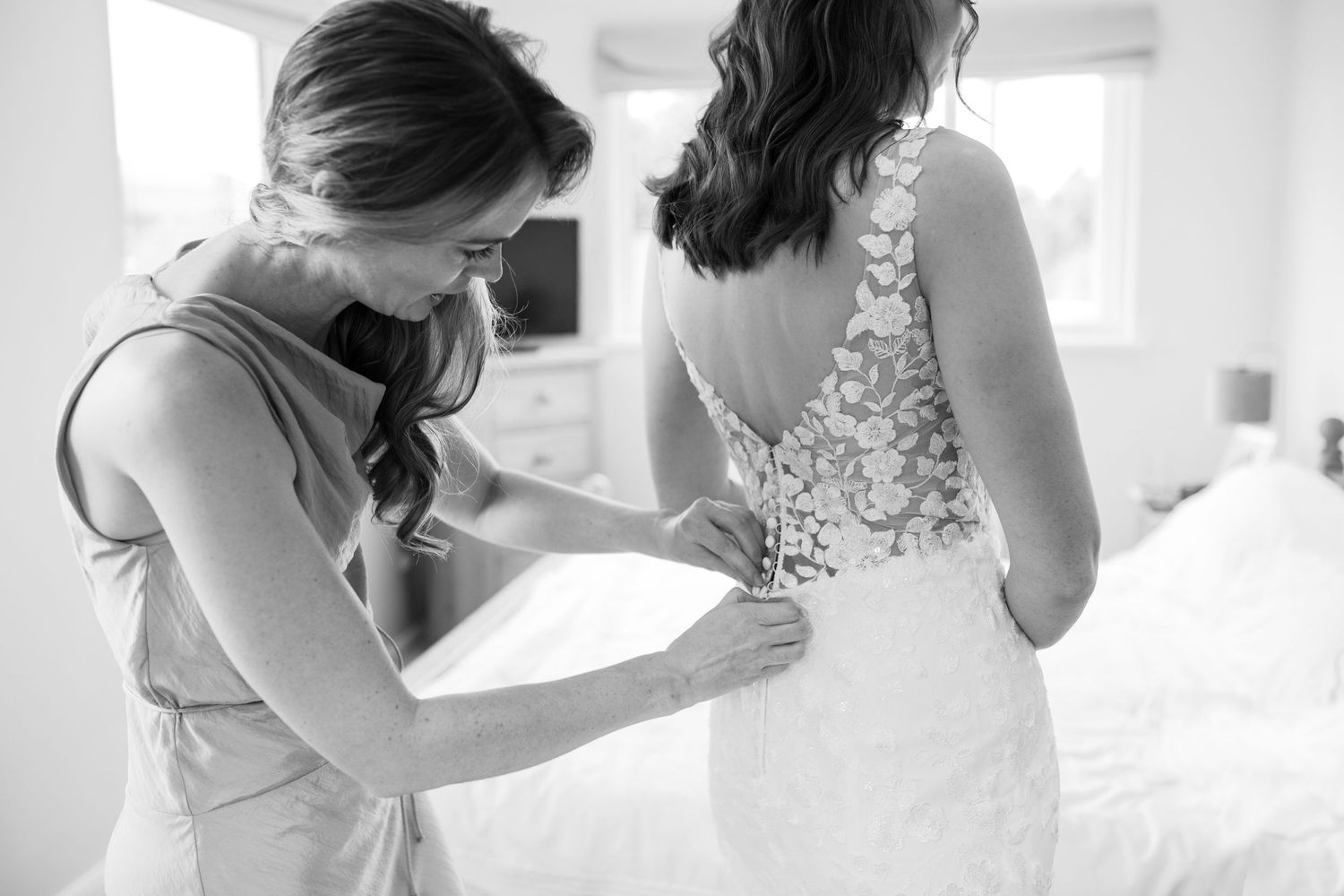 Wedding dress being adjusted in an intimate getting ready moment.