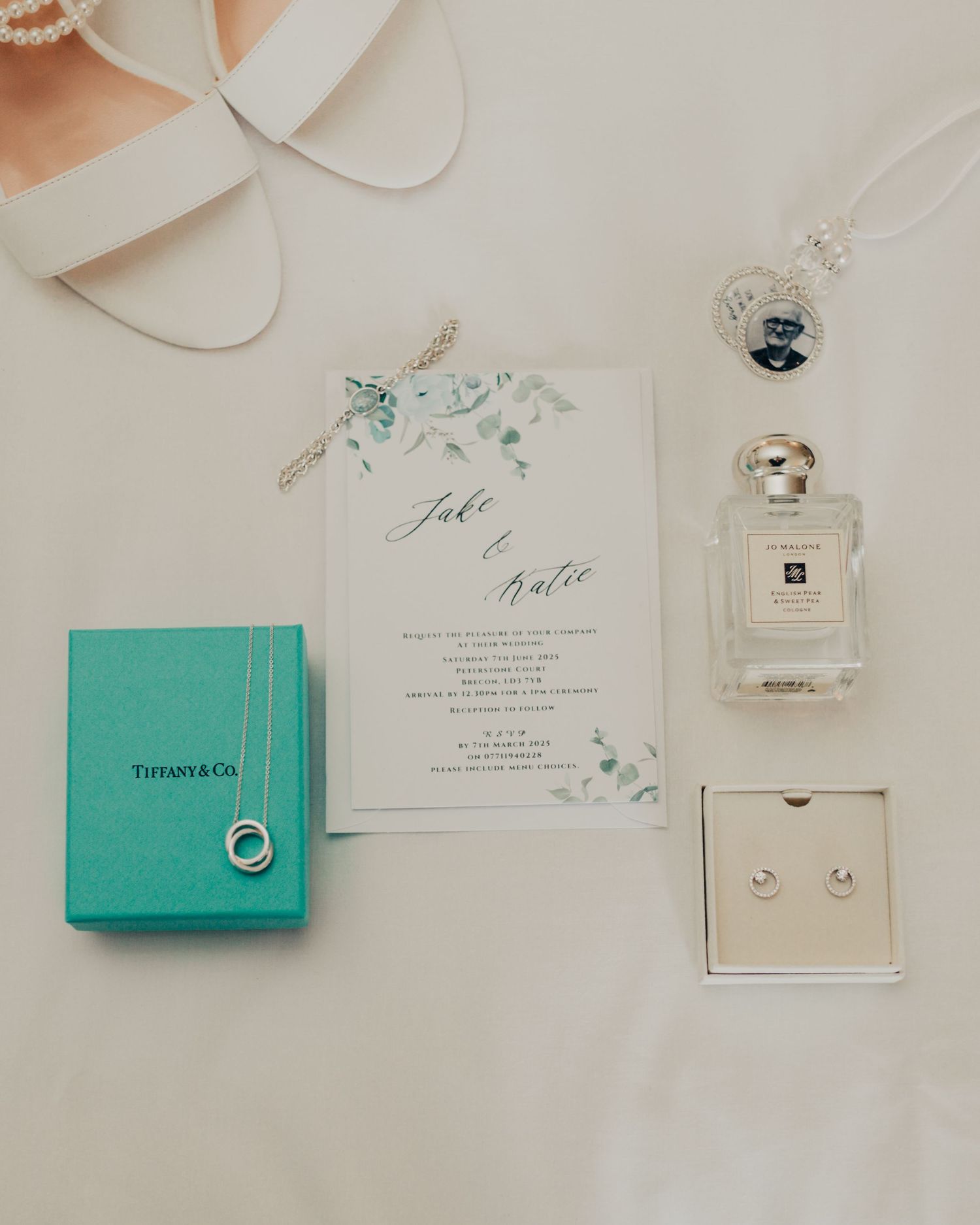 Wedding details flatlay with Tiffany box, invitation, and Jo Malone perfume.