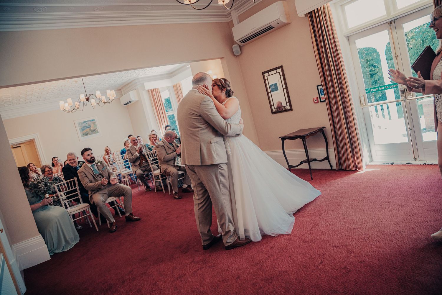 Wedding celebration captured in a spacious venue with red carpeting.