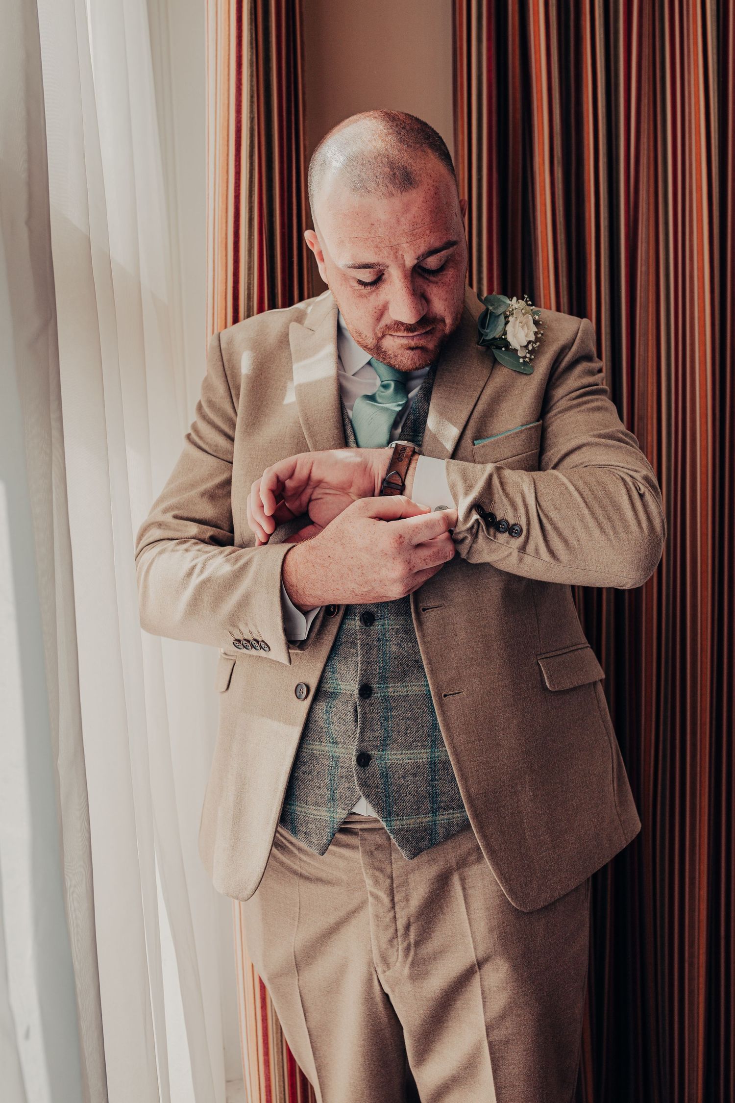 Groom checks watch while getting ready.