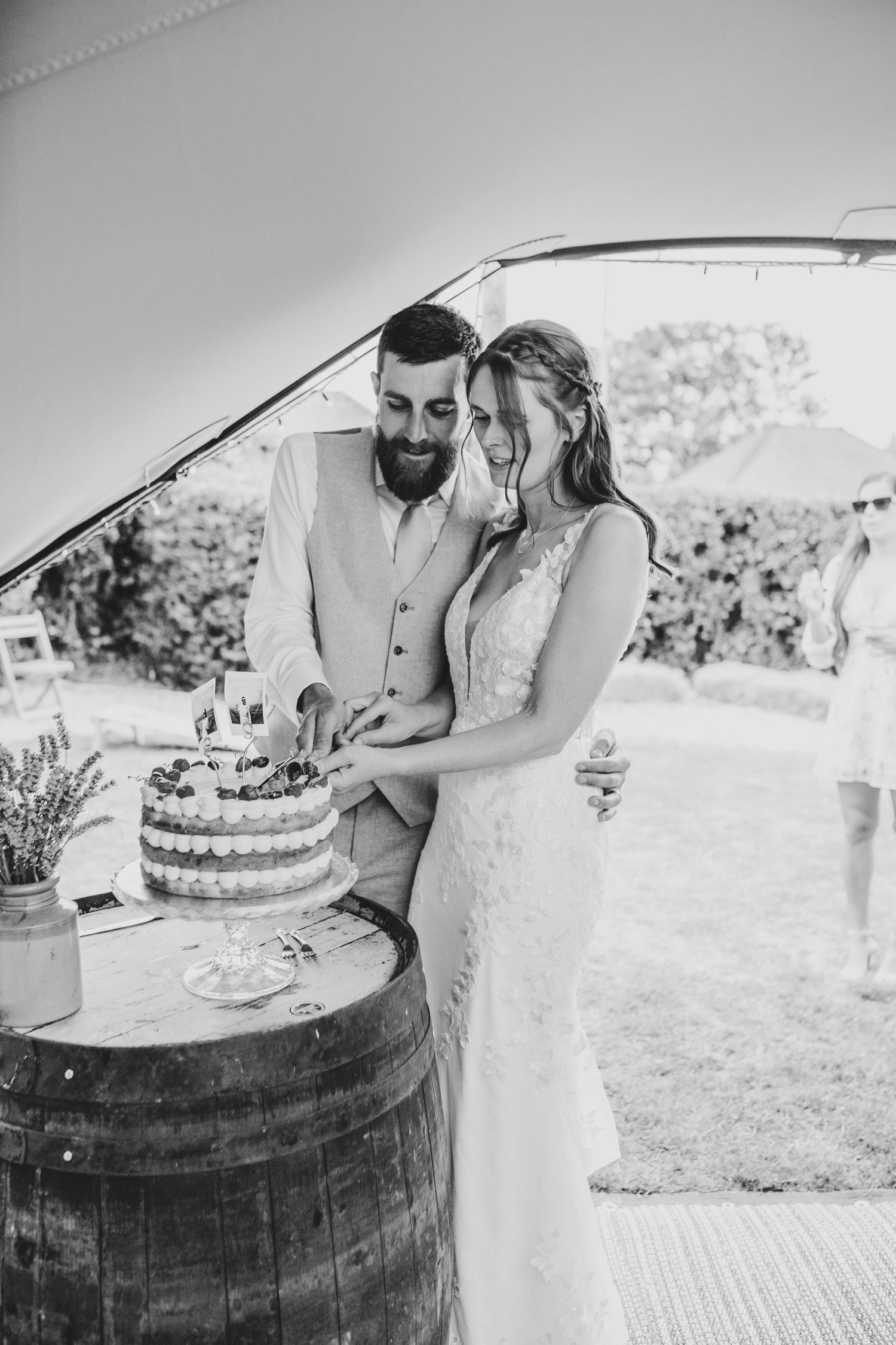 Black and white wedding photos showing couple near rustic wine barrel outdoors.