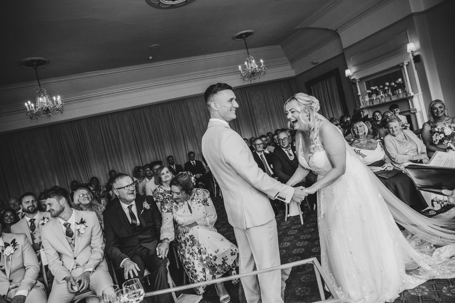 Wedding couple during their ceromony surrounded by guests in an elegant ballroom.