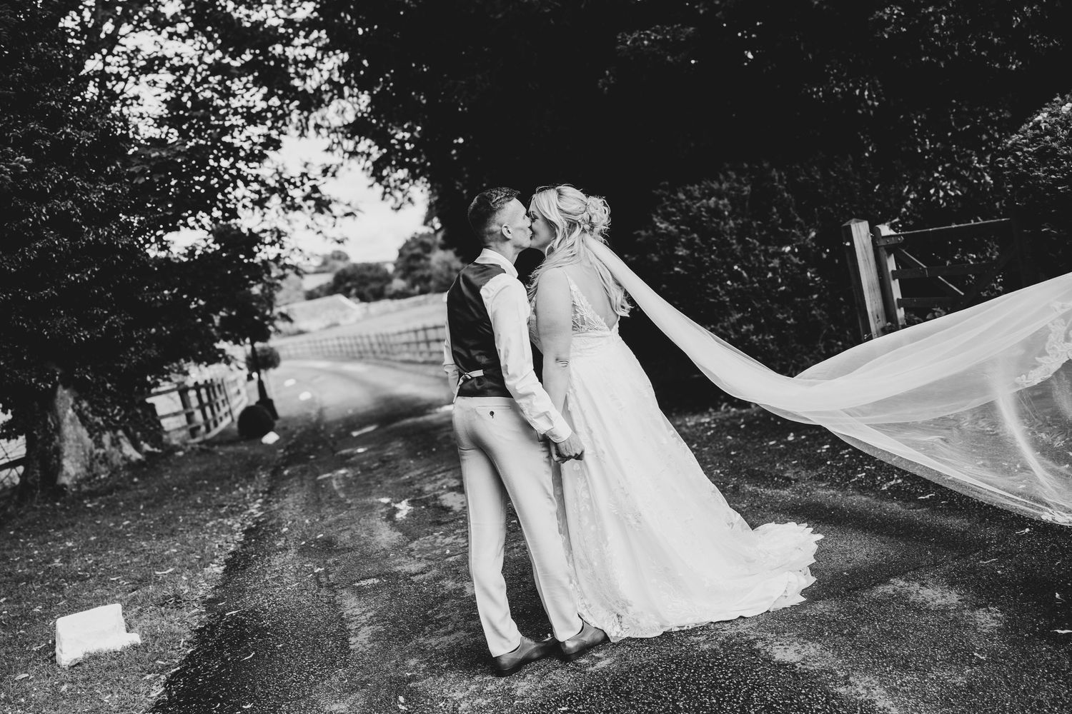 Wedding couple walking through a garden path surrounded by lush greenery.