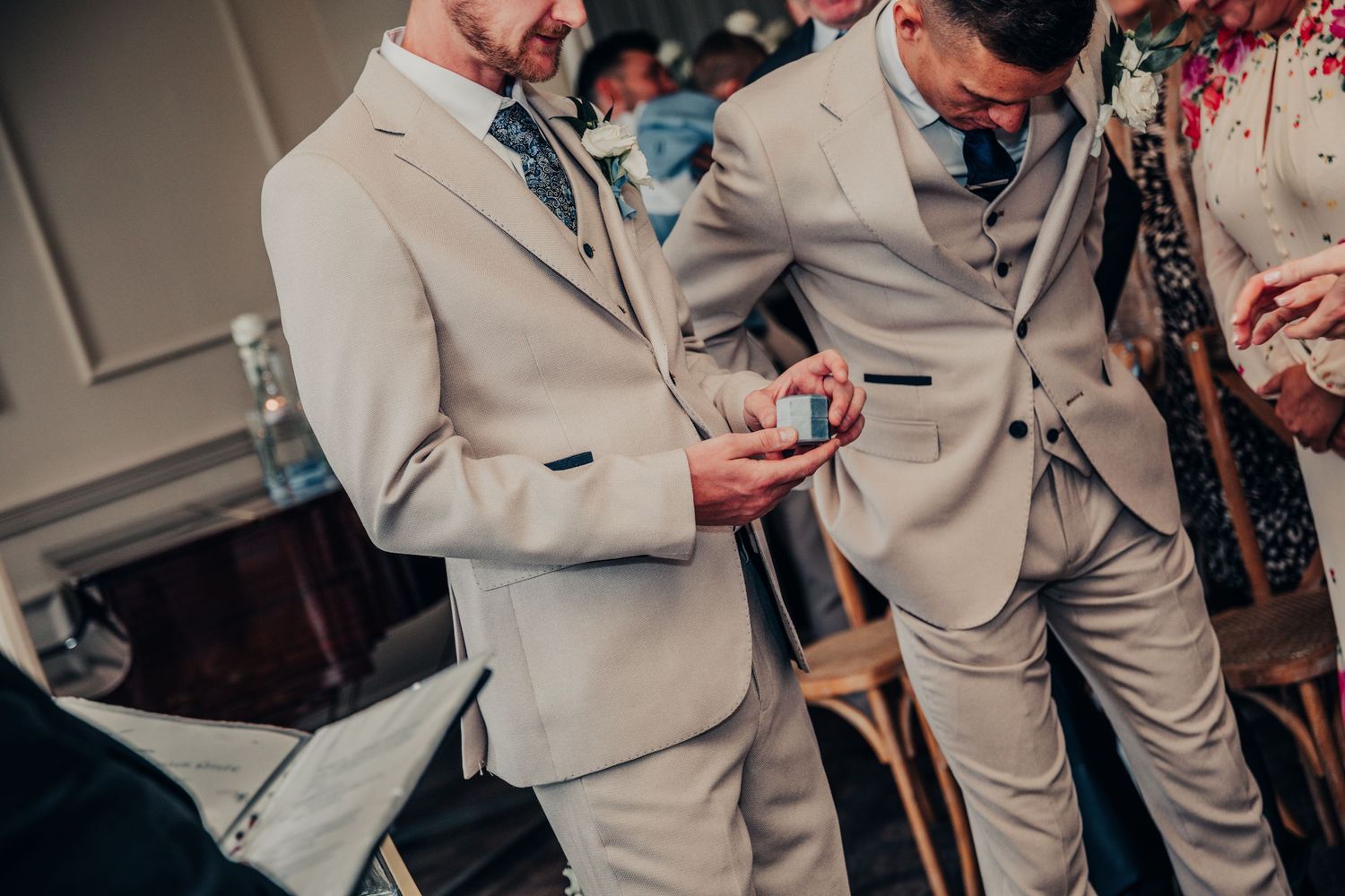 Groomsmen in beige suits adjusting their attire before the ceremony.