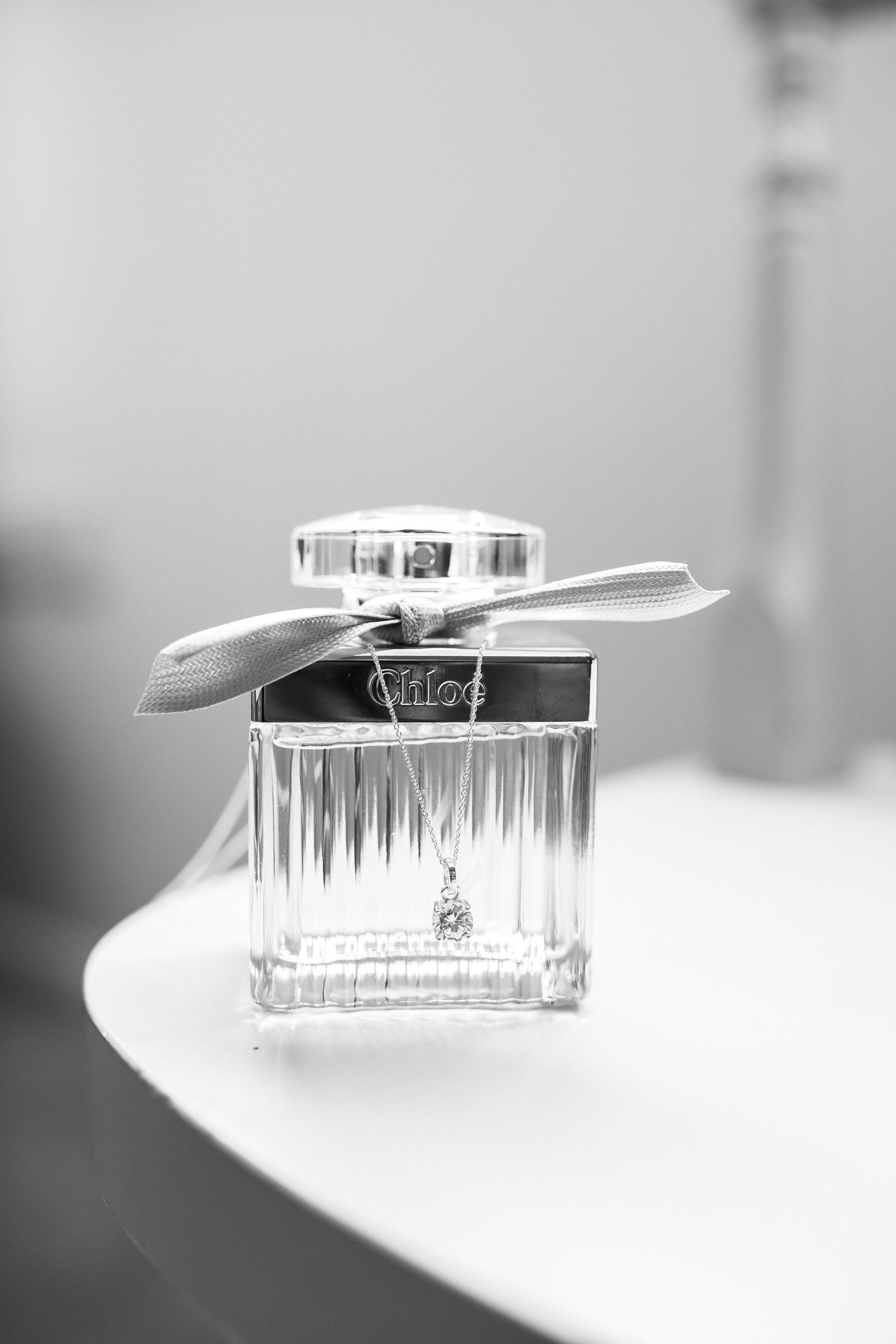 Elegant perfume bottle with ribbon displayed in black and white photography.