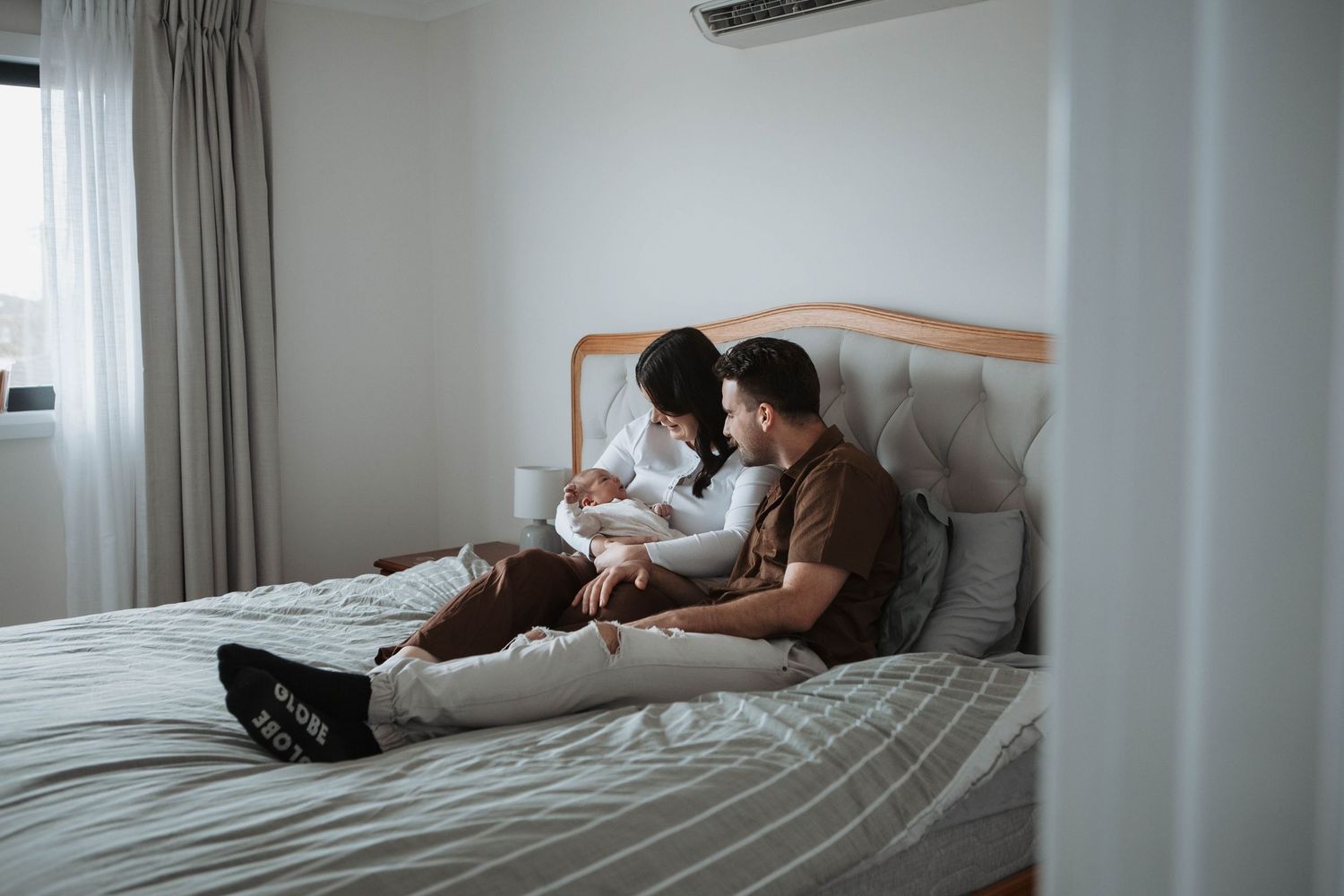 Couple relaxing on a bed together, looking at a book in a bright, modern bedroom.