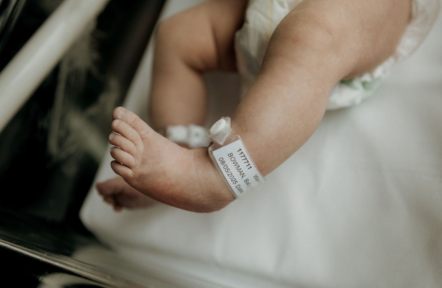 Close-up of a newborn babys tiny feet with a hospital identification bracelet attached.